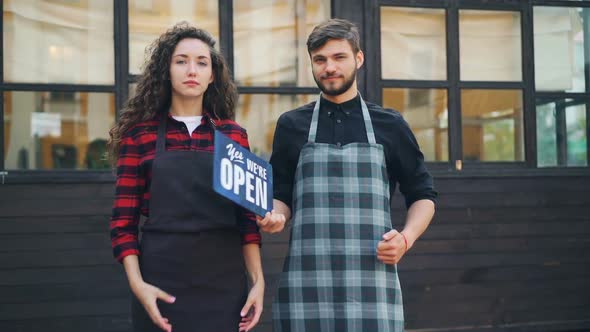 Slow Motion Portrait of Smiling Young People Business Partners Holding Sorry We Are Closed Sign Then