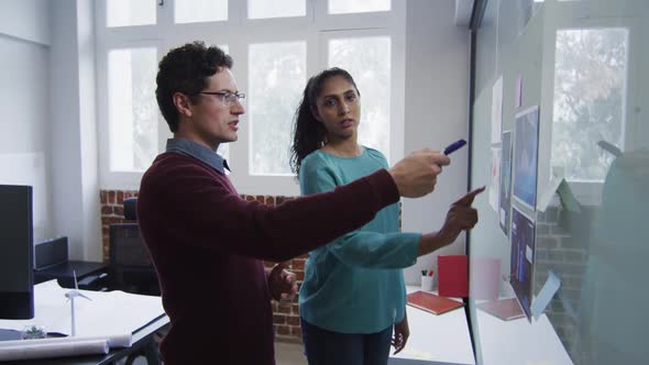 Man and woman discussing over memo notes on white board at office