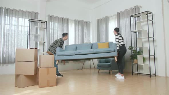 Happy Young Asian Couple Moving New Sofa Into A New House Before Sitting On It To Rest