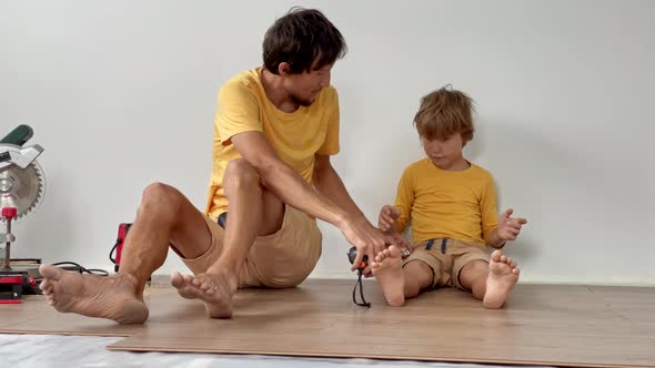 Father and His Little Son Install Laminate on the Floor in Their Apartment