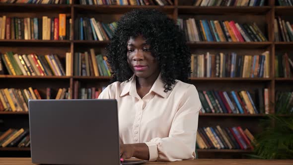 AfricanAmarican Businesswoman Works on Laptop at Table