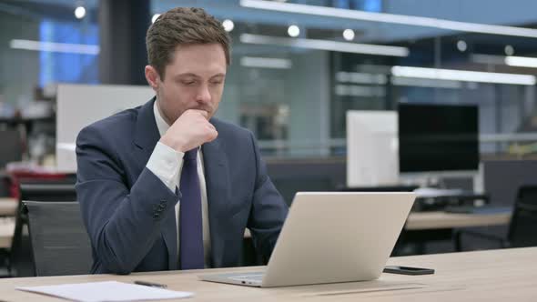 Businessman Thinking While Working on Laptop in Office