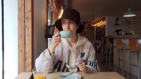 a Girl Has Breakfast in a Cafe