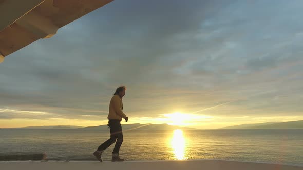 Man running on wall on seaside at sunset