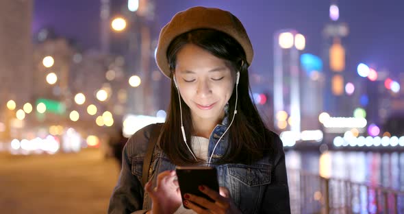 Woman use of mobile phone on earphone at night