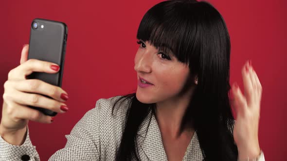 Casual Young Woman 30Years Talking on Phone Having Conversation Via Video Chat Over Red Background