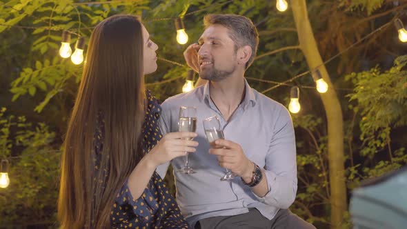 Portrait of Romantic Couple Clinking Glasses and Kissing. Happy Loving Caucasian Man and Woman