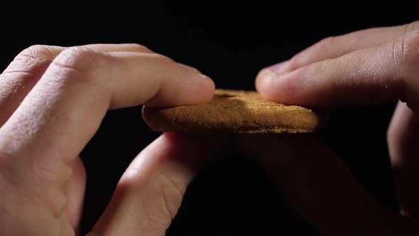 Men's Fingers Hold a Cookie and Then Break It in Half