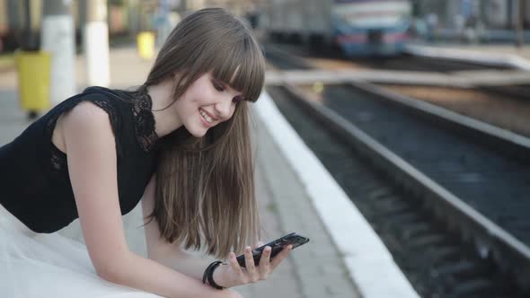 Happy Young Girl Speaking on Mobile Phone on Railway Platform