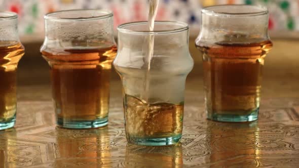 Pouring traditional Moroccan mint tea in glasses 