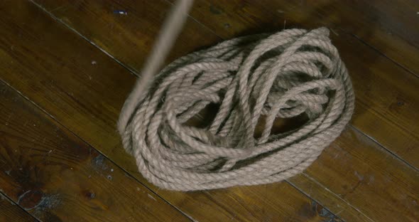 Pirate Unwinds Long Beige Rope Lying on Wooden Floor