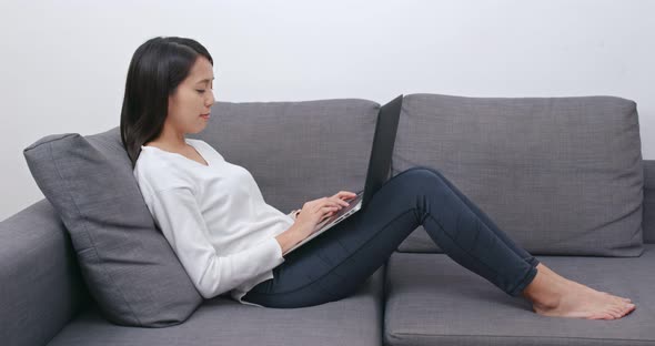 Woman work on computer and lying on sofa