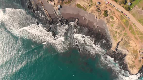 Aerial descend of coast with waves crashing against the rocks and beach, Pichilemu, Chile-4K