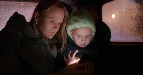 Mother and Kid Using Phone During Night Car Travel