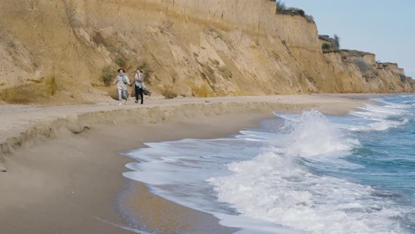 Woman Couple Run Holding Hands Along the Sea Beach