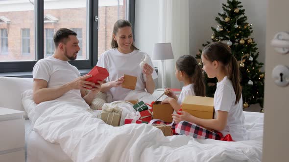 Happy Family with Christmas Gifts in Bed at Home