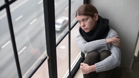 A sad young woman, a resident of the city, leaned her head against the window