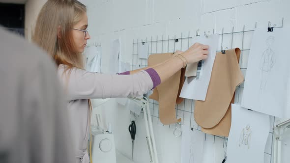 Attractive Girl Dressmaker Choosing Material for New Clothing Working in Studio