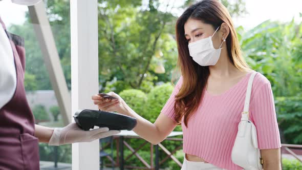 Young Asia female wear face mask making contactless credit card payment and take out food