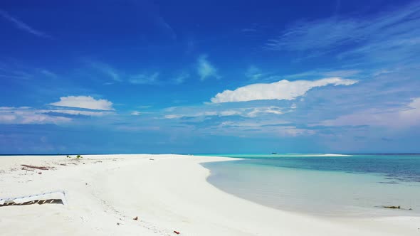 Wide angle flying travel shot of a paradise sunny white sand beach and aqua blue water background in