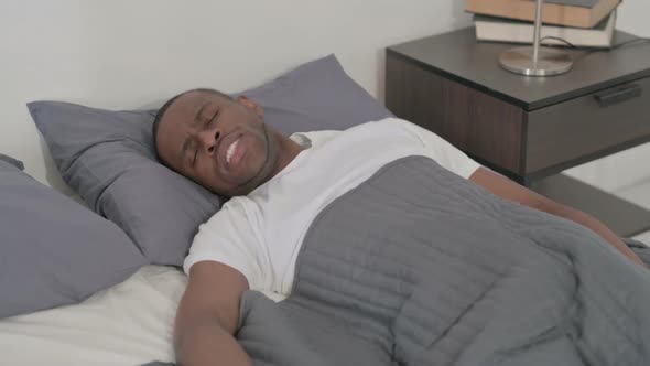 African Man Having Back Pain While Sleeping in Bed