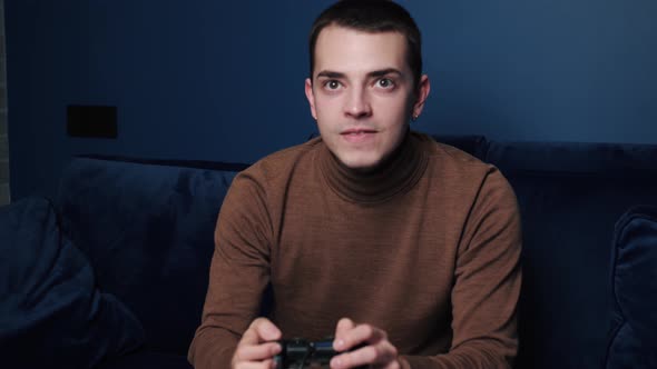 Emotional Caucasian Man Holding Controller, Playing Games Alone on Sofa at Home. Focused Man Using