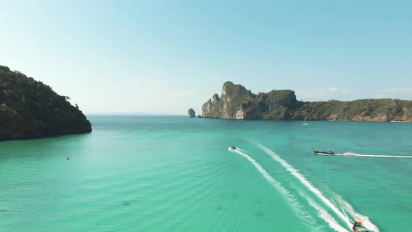 Pristine Loh Dalum Bay on a clear sunny day, crossed by motor boats in Ko Phi Phi Island, Thailand