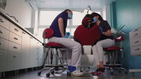 Doctors Dentists Woman and Man in Medical Masks Serve Patient in Dental Clinic