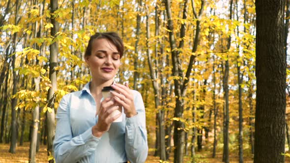 Woman with coffee in park. Young woman relaxing with cup of coffee in park