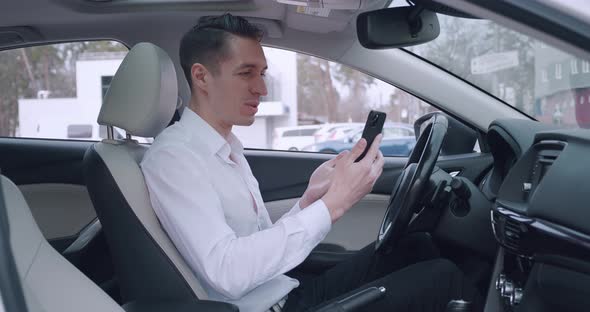 Young Businessman Having Video Chat Using Smartphone While Sitting in a Car