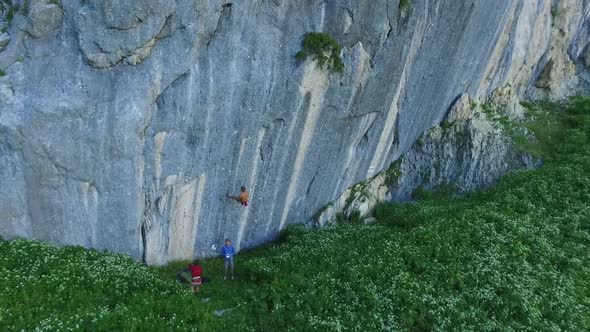 Aerial drone view of a man rock climbing up a mountain.