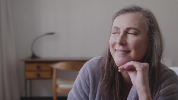 Woman with her hand on her chin smiling at home