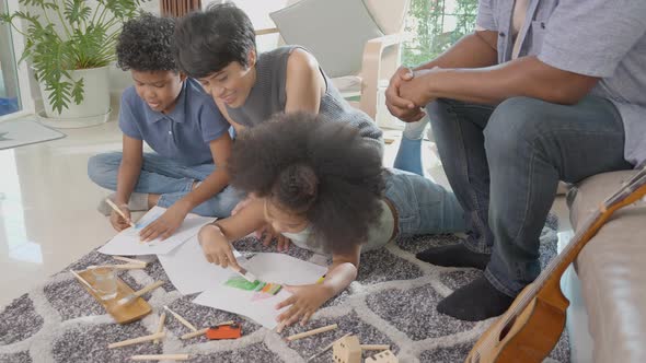 Happiness family with father and mother looking children drawing with colorful pencils.