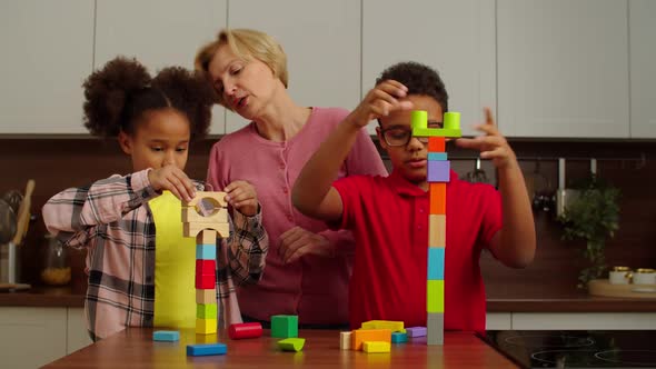 Carefree Multicultural Kids and Grandmother Playing with Toy Building Blocks
