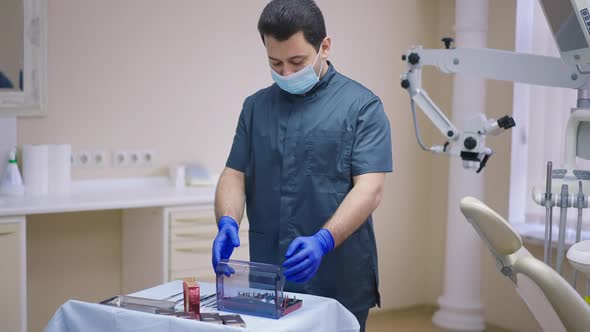 Male Middle Eastern Dentist Opening Dental Surgical Kit in Slow Motion Standing in Office Indoors