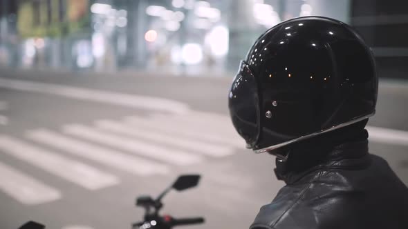 Young Attractive Man Motorcyclist with His Helmet and Custom Motorcycle on Night Street