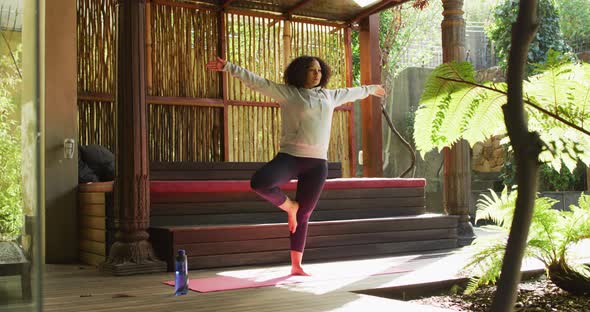 African american woman practicing yoga and meditating at vacation home