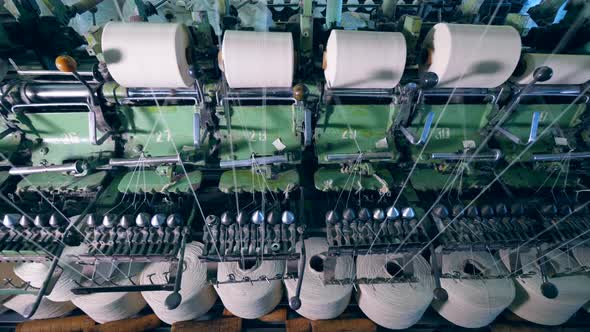 Sewing Clews with White Threads Rotating on Textile Factory Machines