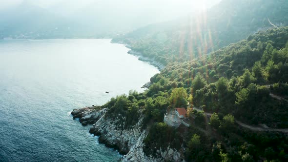 Drone Flying Over House on Rocky Coast Line with Beautiful Turquoise Sea Water