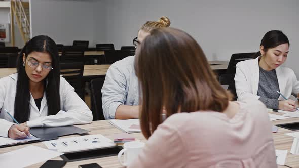 Unknown Boss Discussing Details of Startup Project with Young Team of Diverse Colleagues Sitting at