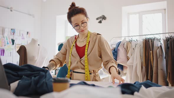 Young Woman Tailor Working at Workshop with Patterns and Fabric Making Clothes Tracking Shot