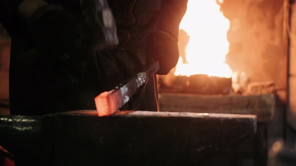 Blacksmith Hammering Red Hot Metal Piece on an Anvil. The Hammer of Smith Beat on Glowing Hot Metal