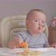 Mom feeds a newborn baby aged 12-17 months spaghetti with tomato sauce. Toddler eats pasta - VideoHive Item for Sale