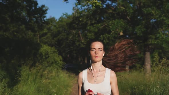 Young Woman Run in the Park Among Green Trees