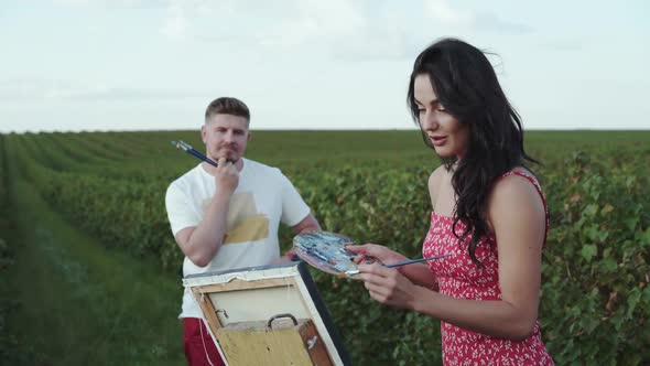 Happy Woman Having a Fun Small Talk with Man During Painting in a Field