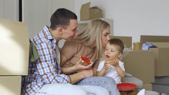 Happy Family Householders with Kid Sitting on Couch at New Home at Moving Day