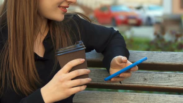 Woman Drinks Coffee on the Bench