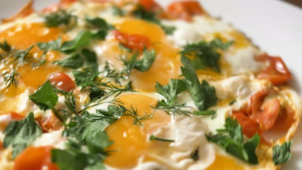 Plate with Roasted Eggs with Tomato Slices and Greenery