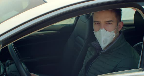 Man in Car with Surgical Mask on Face Against Coronavirus Disease 2019. COVID-19 Pandemic