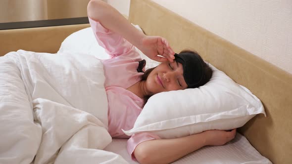 Lady Removes Sleeping Mask Stretches Arms Lying in Bed